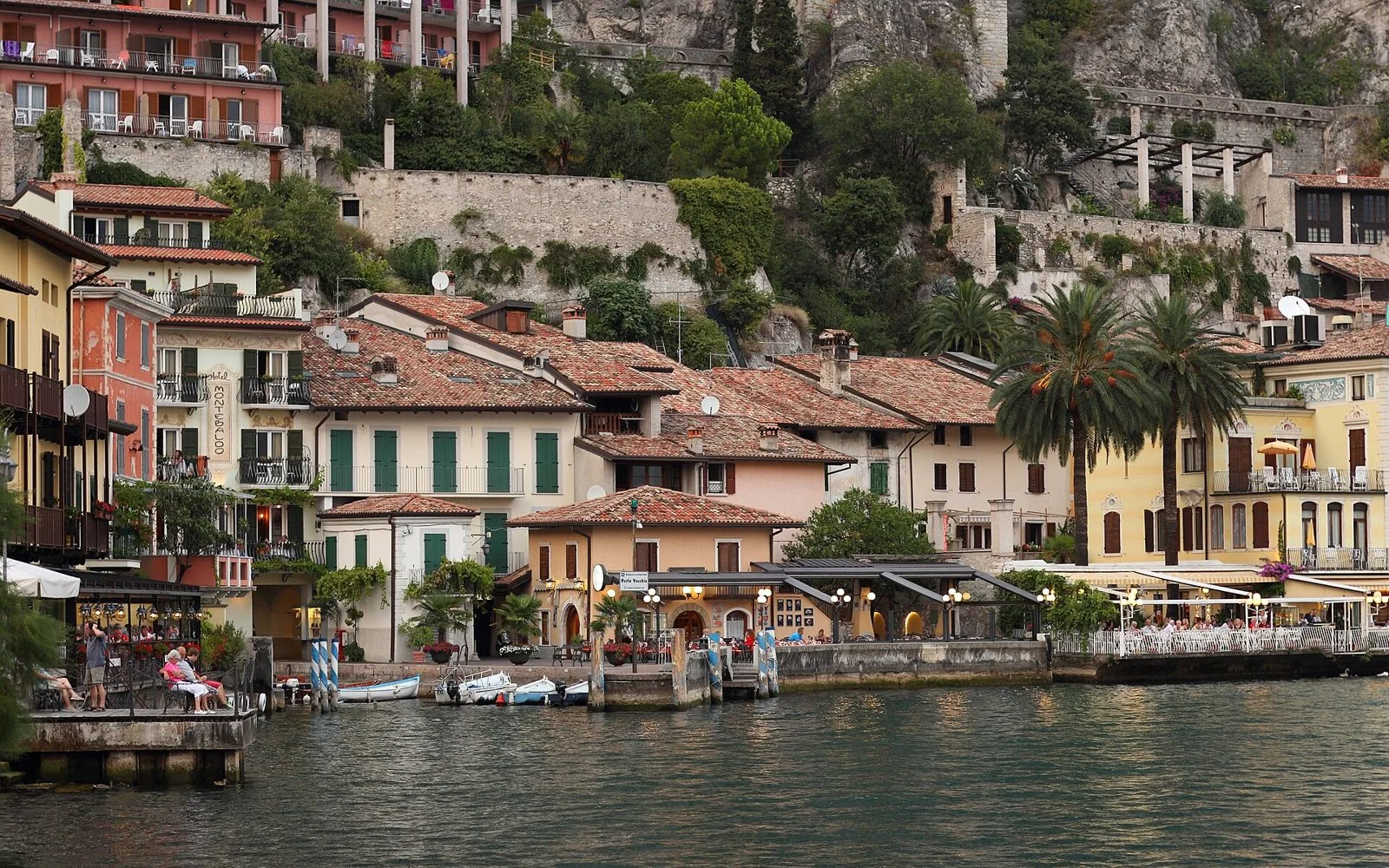 Le case colorate e il Porto Vecchio di Limone sul Garda al tramonto, ai piedi della parete rocciosa