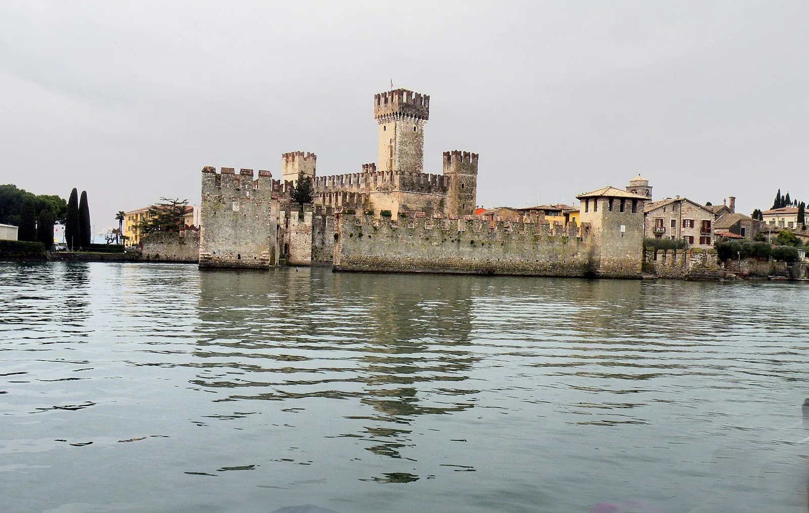 Il castello scaligero di Sirmione con torri merlate e mura che emergono dall'acqua del lago